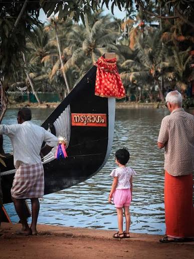 The Nadubhagam Chundan at the water's edge, its Malayalam nameplate on the black hull